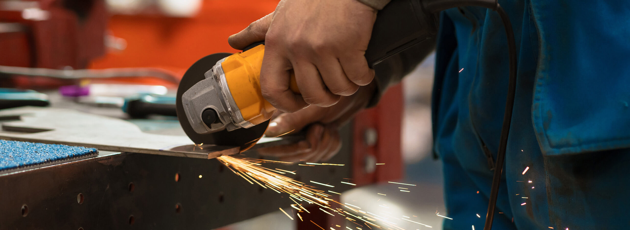 A person sawing a piece of steel with sparks coming off it.